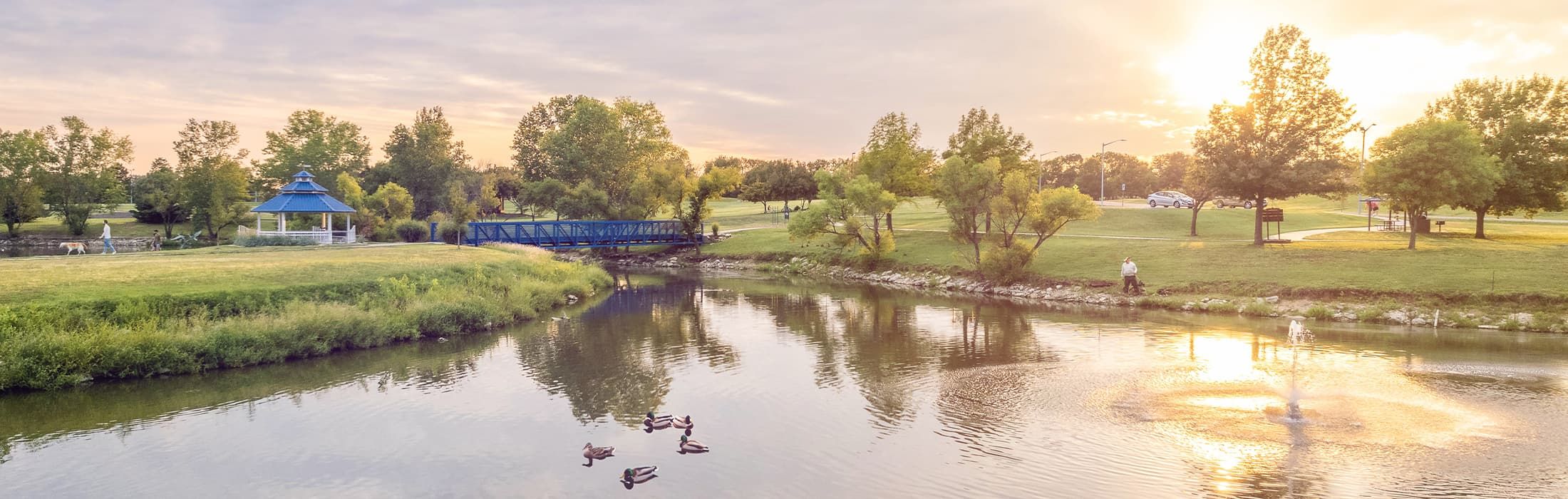 The gazebo and footbridge beside the fishing pond at High Park in Derby at sunset