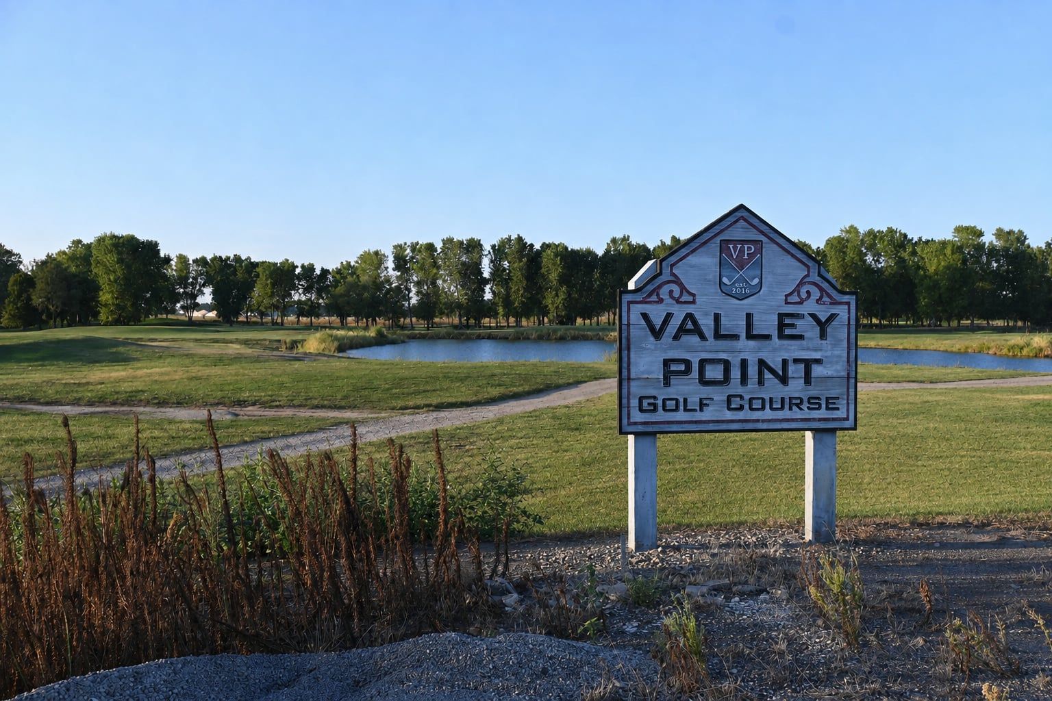 The Valley Point Golf Course sign beside the course's pond and fairways