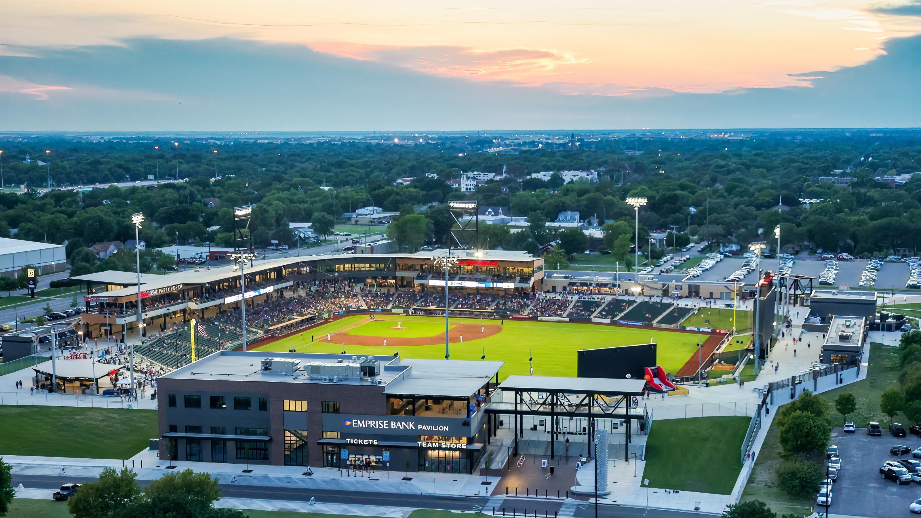 An aerial view of the Wichita Wind Surge ballpark at sunset, with the city stretching to the horizon